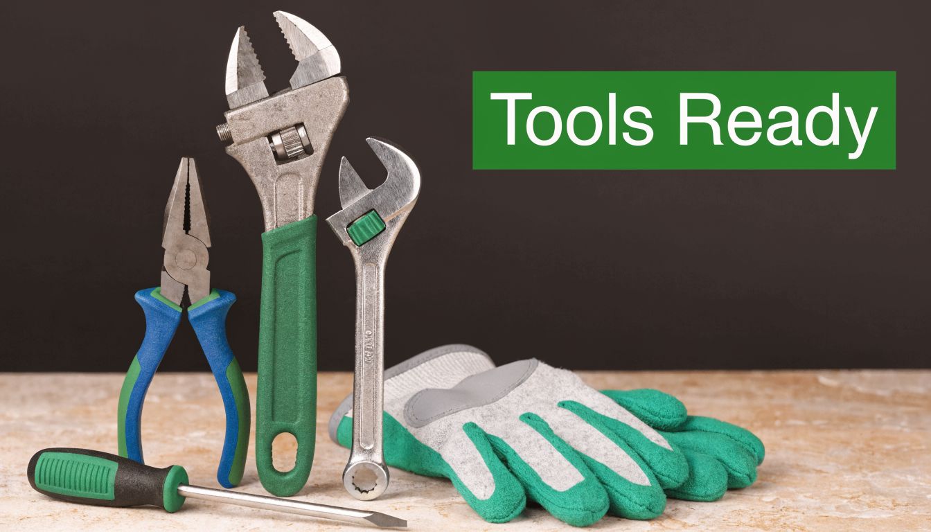 A collection of construction tools including wrenches, pliers, a screwdriver, and safety gloves on a stone surface.