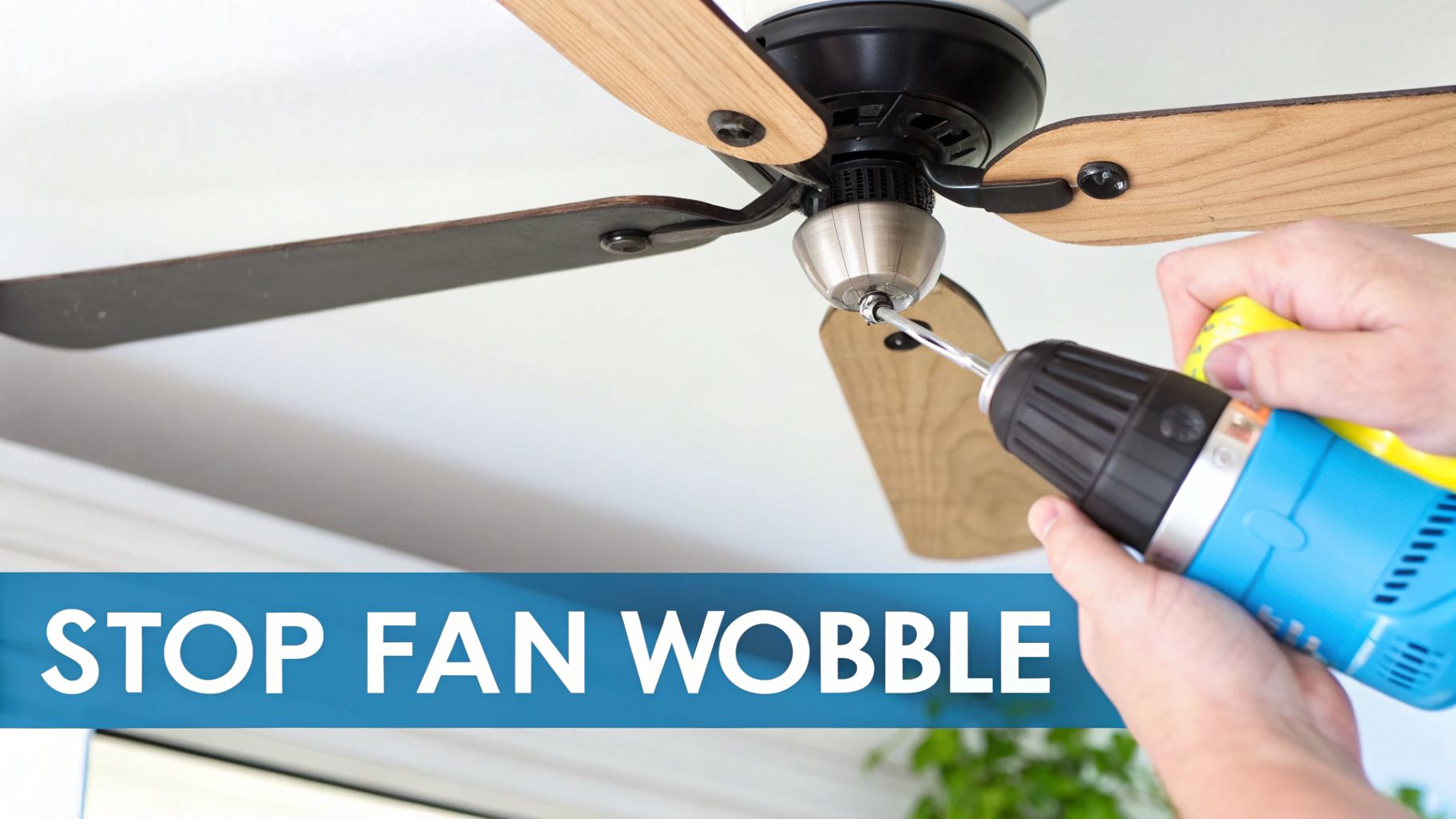 A person's hands use a power drill to tighten a screw on a ceiling fan with wooden blades. A blue banner reads "STOP FAN WOBBLE".
