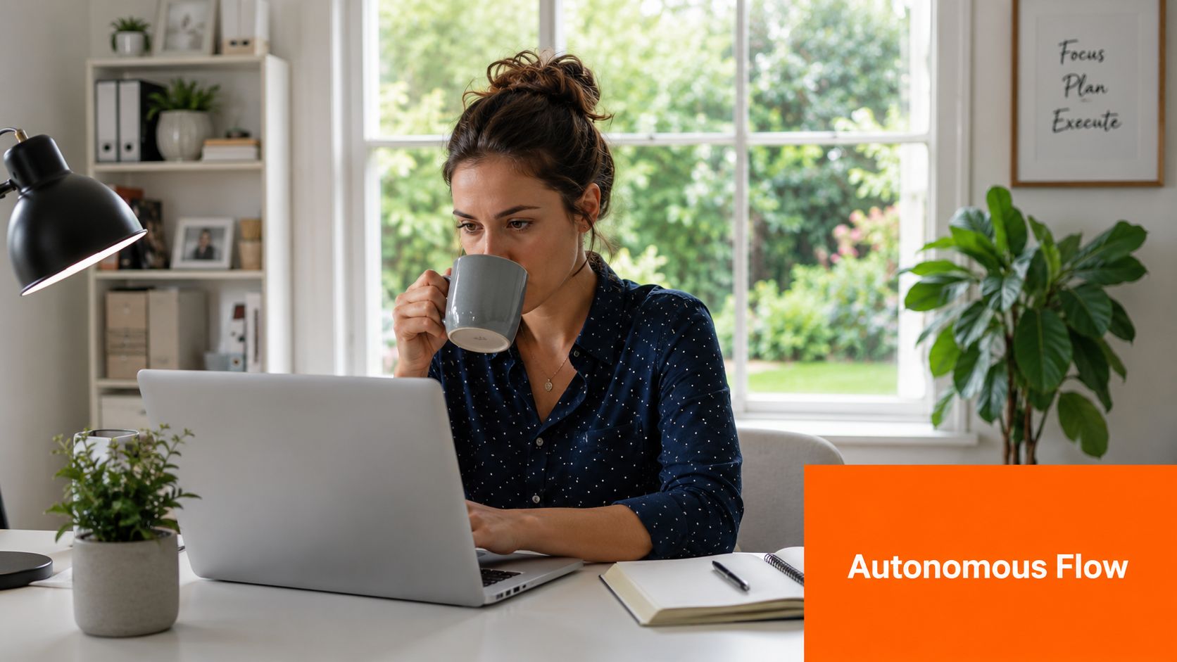 A professional woman drinking coffee while working on a laptop at a home office desk.