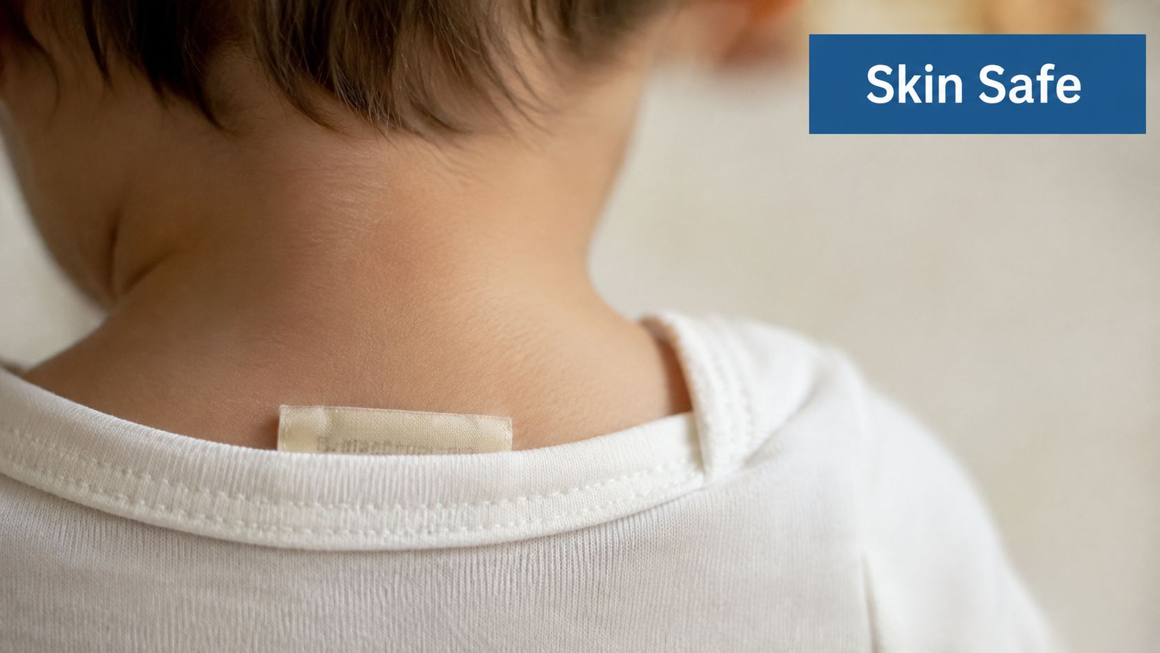 A close up view of a small tag inside the neckline of a white baby t-shirt.