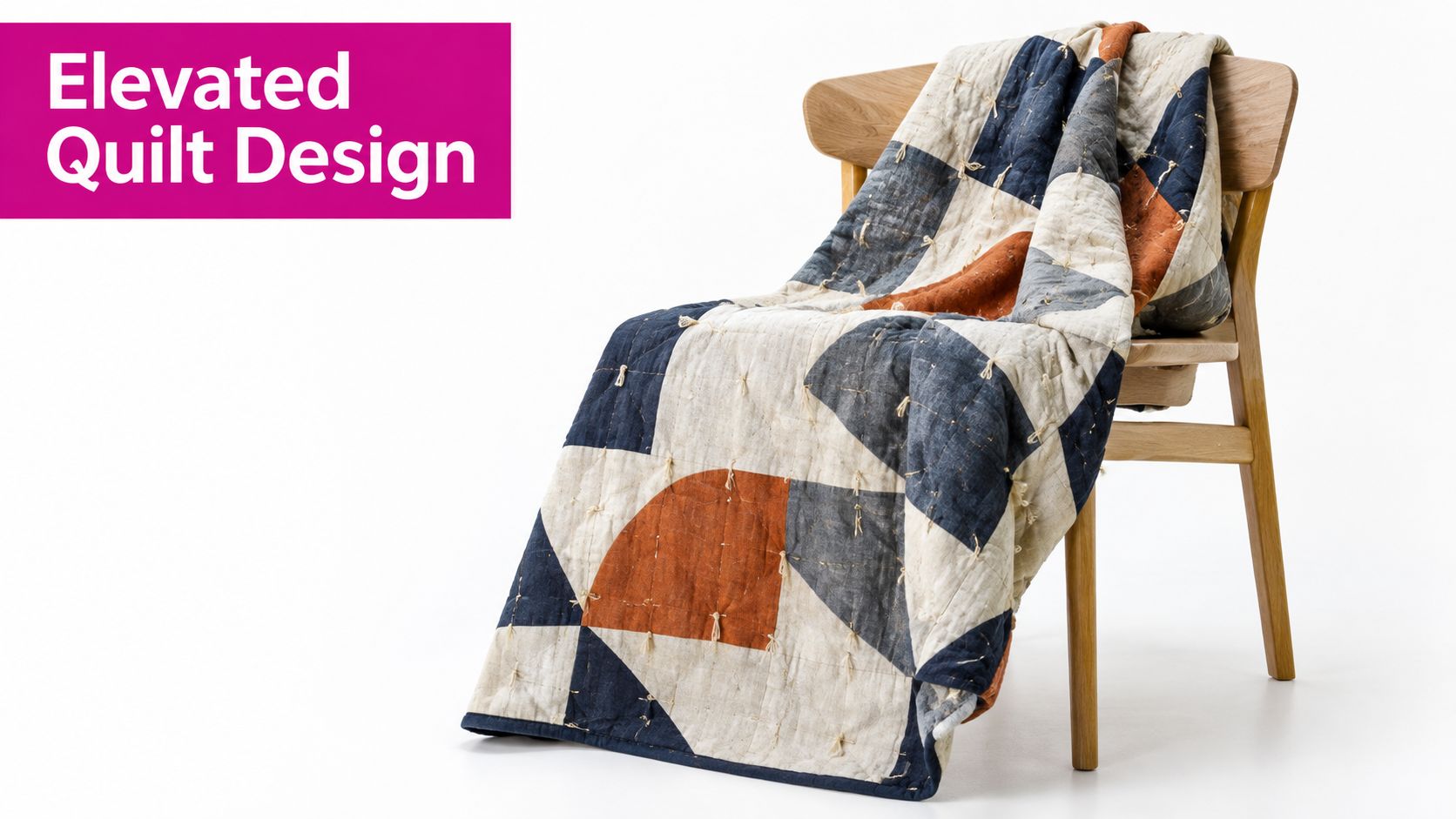 A modern patchwork quilt with geometric shapes in cream, blue, and rust orange draped over a wooden chair.
