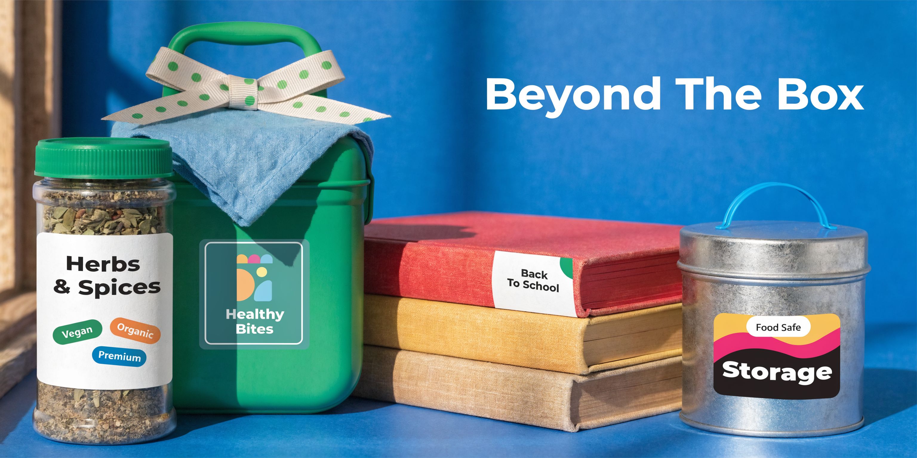 A lunch box, herb jar, and stack of books featuring decorative gift tag stickers on a blue background.