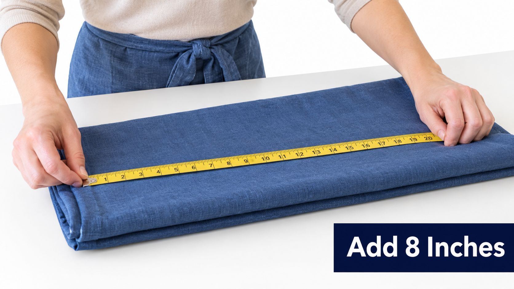 A person measuring a folded piece of blue fabric with a yellow tape measure on a table.