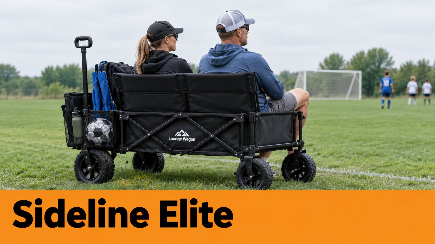 A couple sits on a black Lounge Wagon folding bench wagon on a soccer field grass.