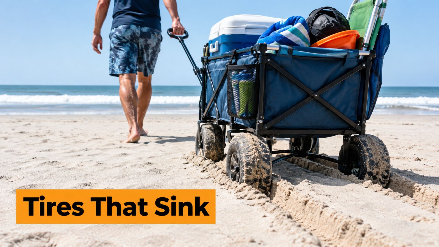 A man pulls a beach wagon with narrow wheels sinking into the soft sand on a sunny beach.