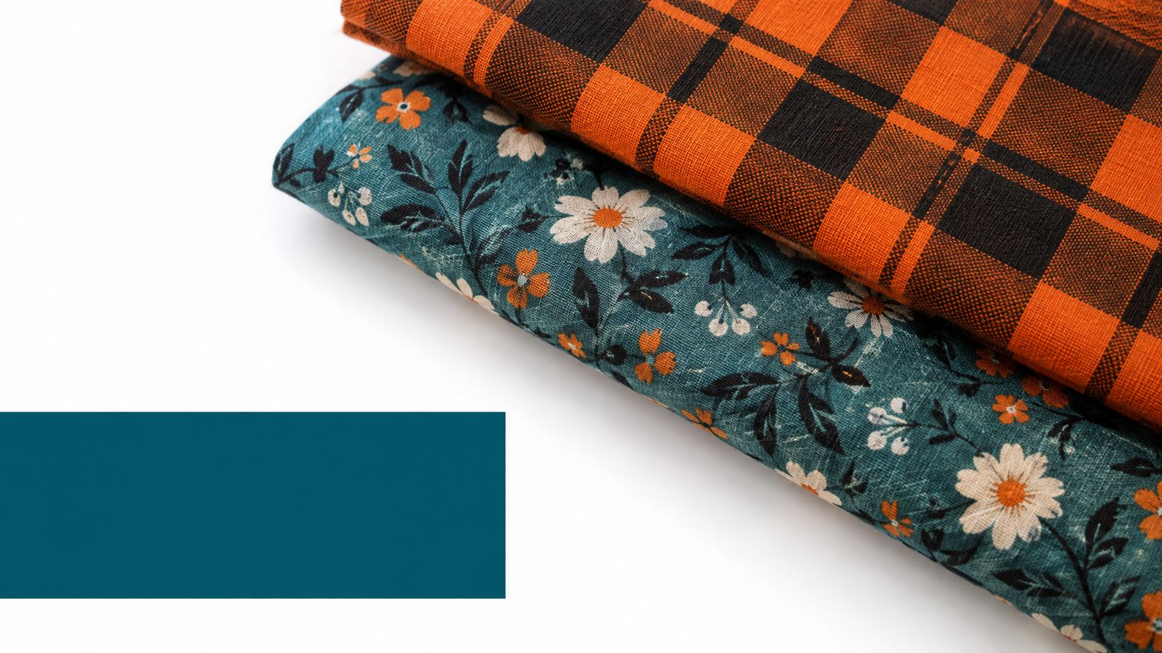 Two folded fabrics, one with an orange and black plaid pattern and one with dark floral print.