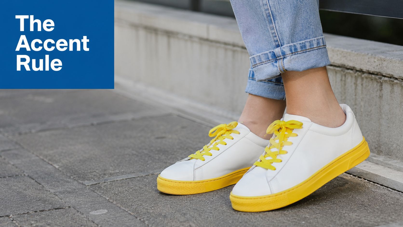 A person wears clean white leather sneakers with vibrant yellow soles and matching yellow laces with light blue jeans.