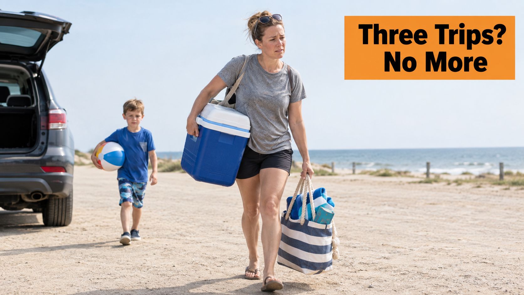 A mother carrying a cooler and tote bag while her son walks with a beach ball.