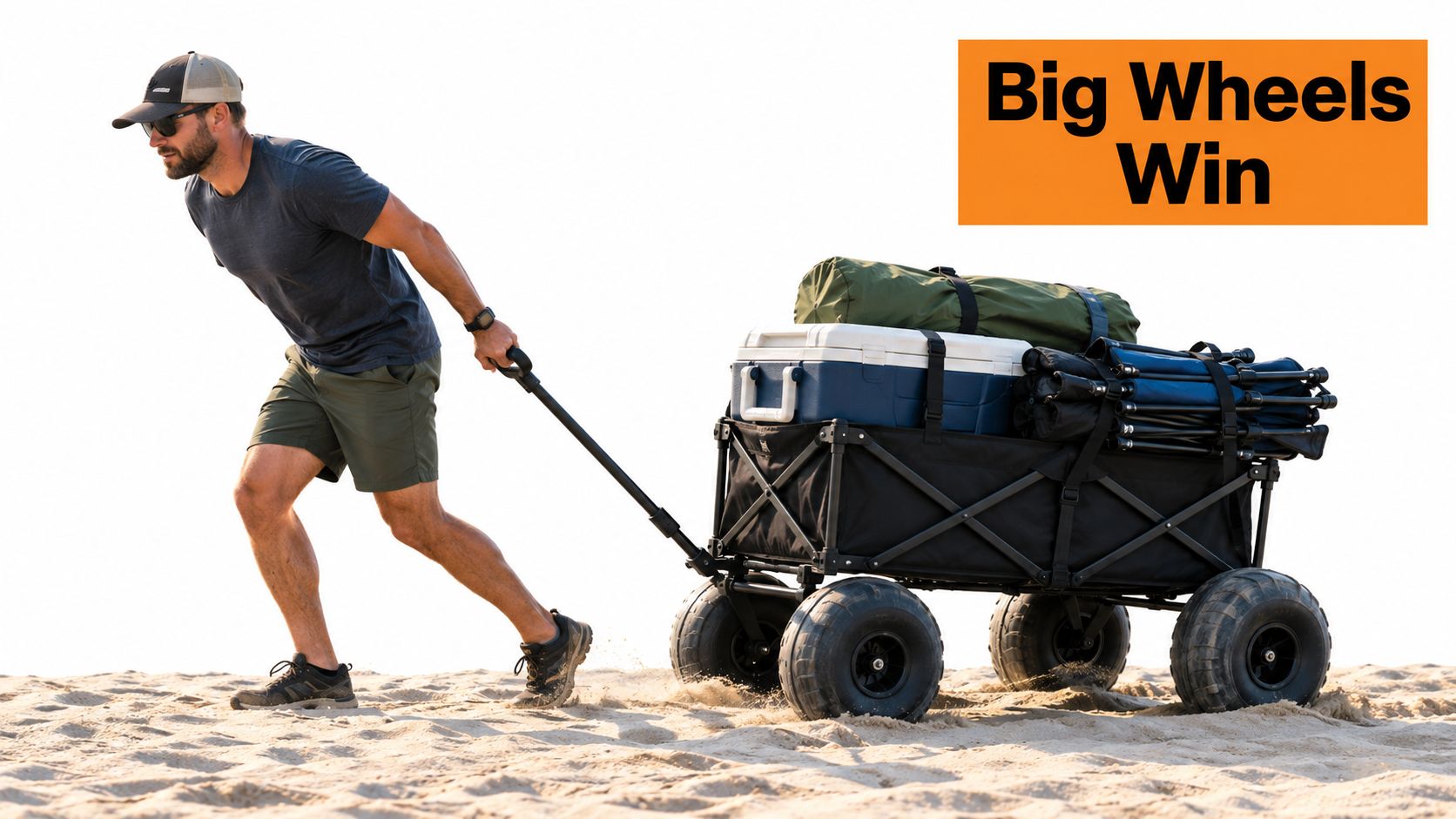 A man pulling a heavy-duty wagon with large wheels across a sandy beach filled with outdoor gear.
