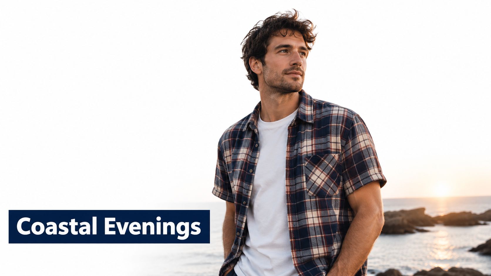 A young man wearing a casual plaid short sleeve flannel shirt standing by the sea during sunset.