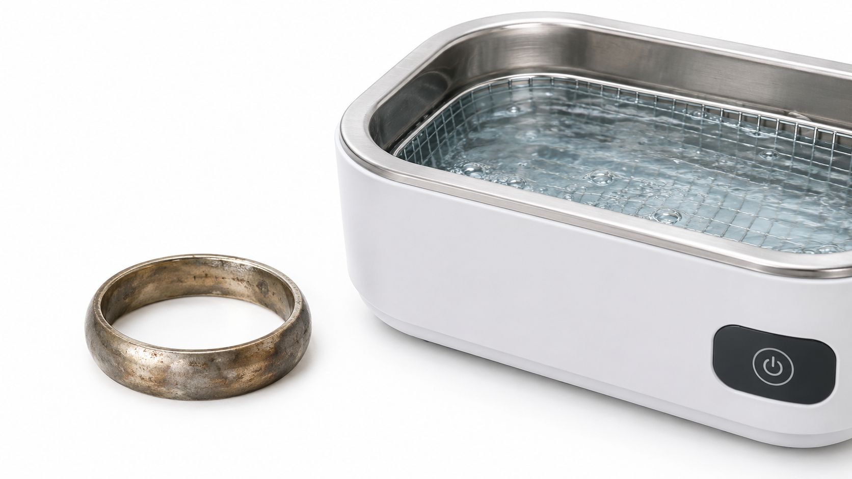 A tarnished metal ring placed next to an ultrasonic cleaner filled with water for deep cleaning.