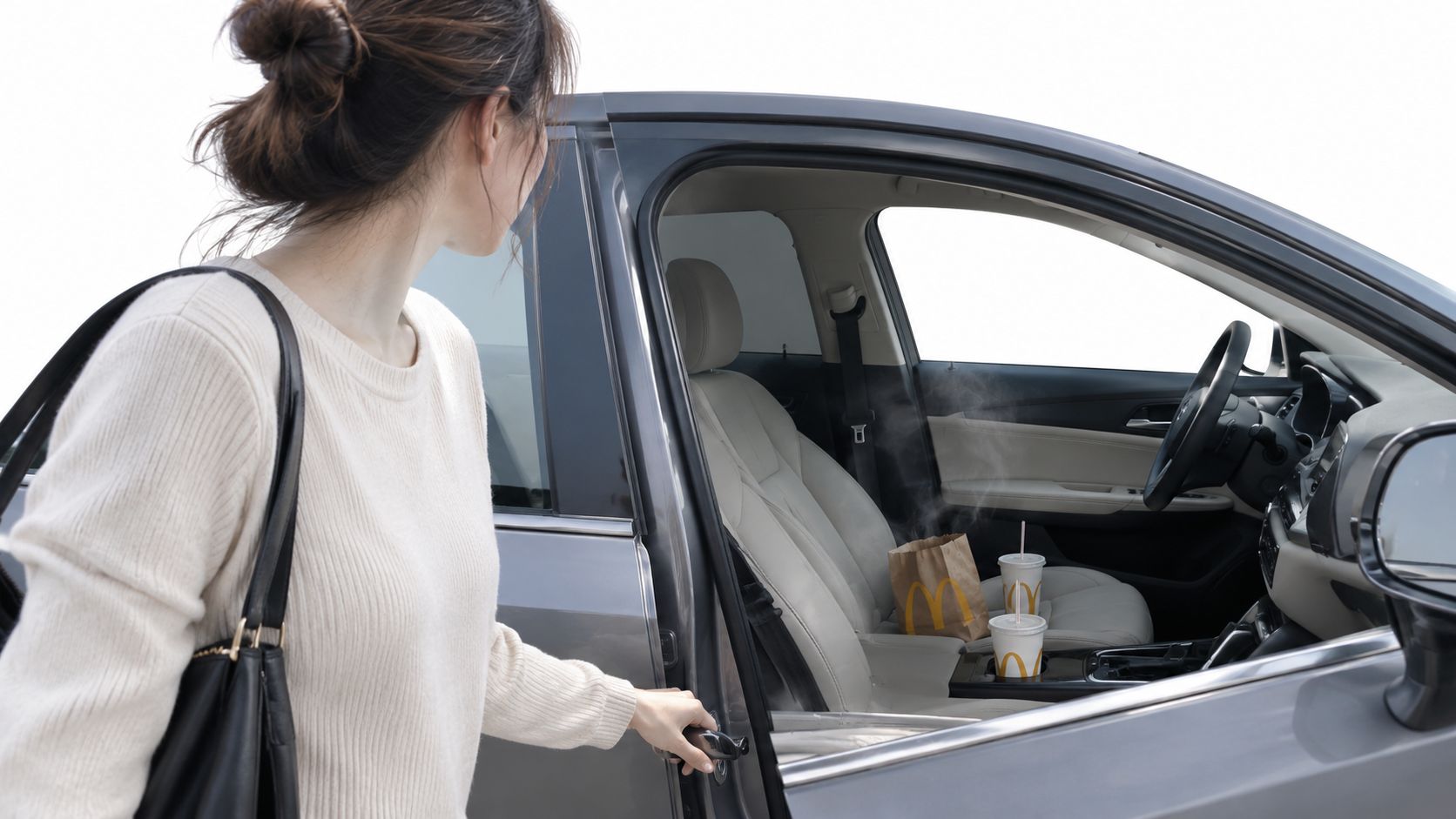 A woman opens her car door to find a steamy McDonald's meal sitting on the front seat.