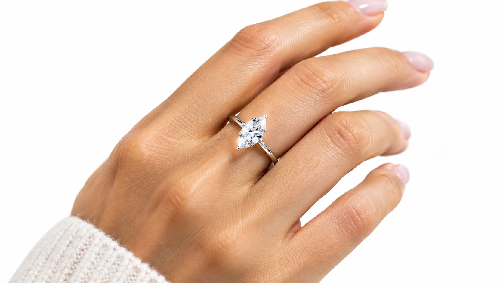 A close-up of a elegant marquise cut white sapphire ring set in shiny sterling silver on a finger.