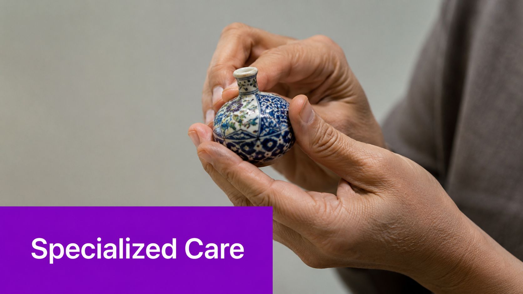 A pair of hands gently holding a delicate, small, ornately painted ceramic vase with specialized care.