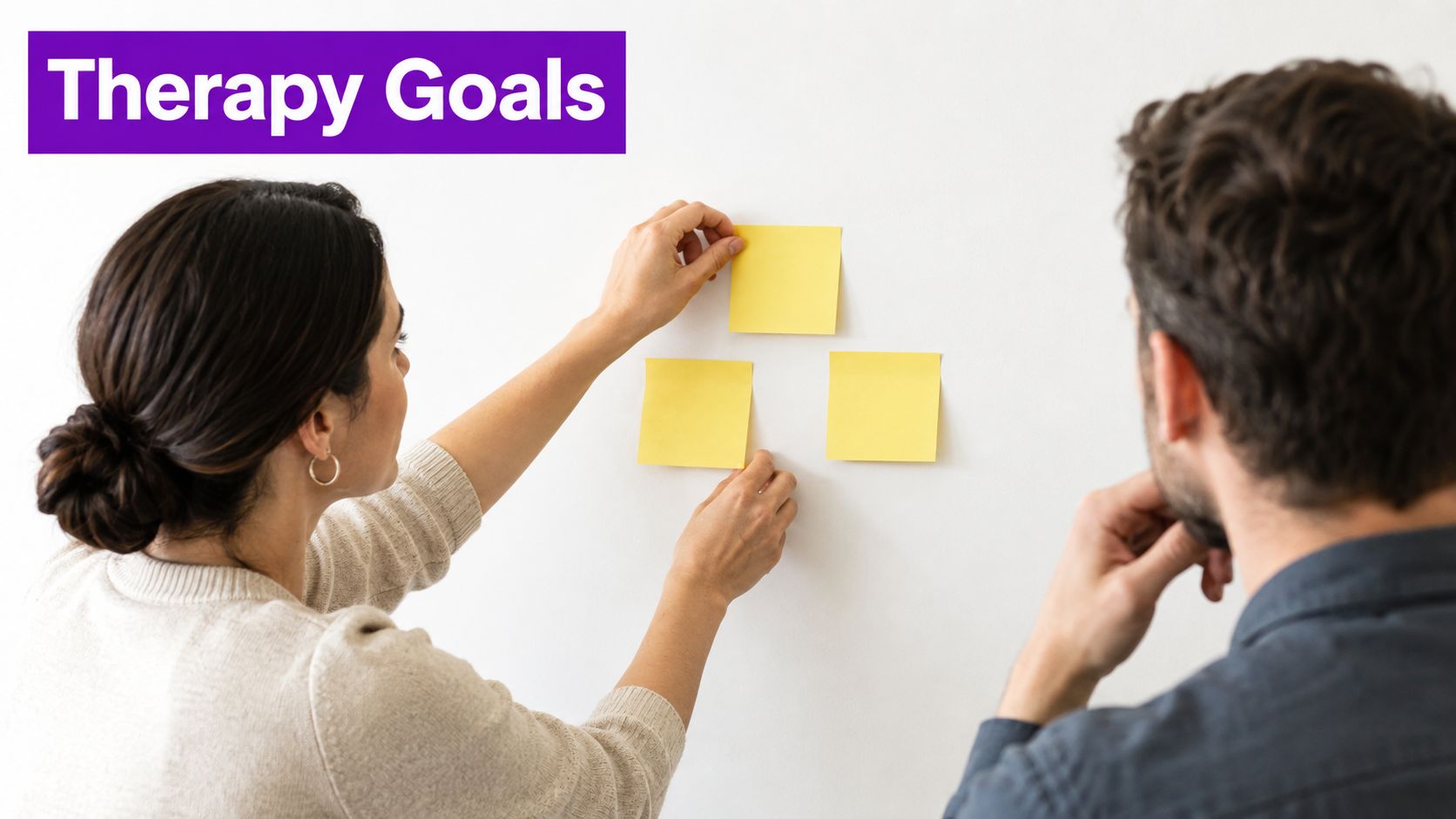 A therapist and client collaborating by placing yellow sticky notes on a wall during a session.