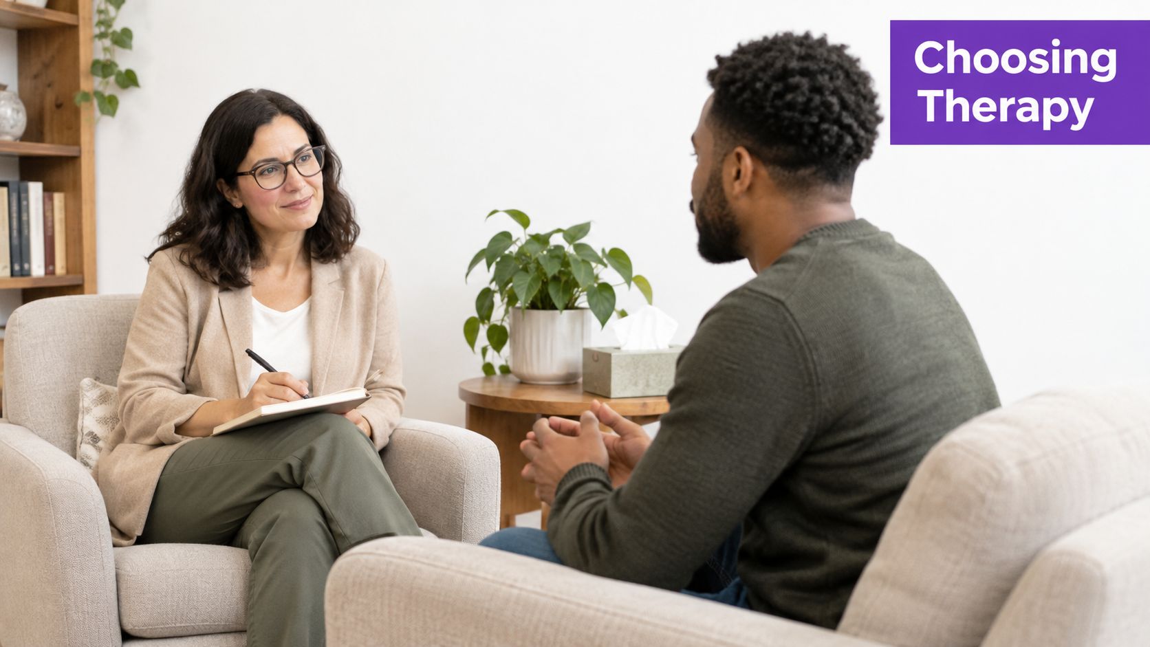 A professional female therapist in a light blazer listens to a male patient during a counseling session.