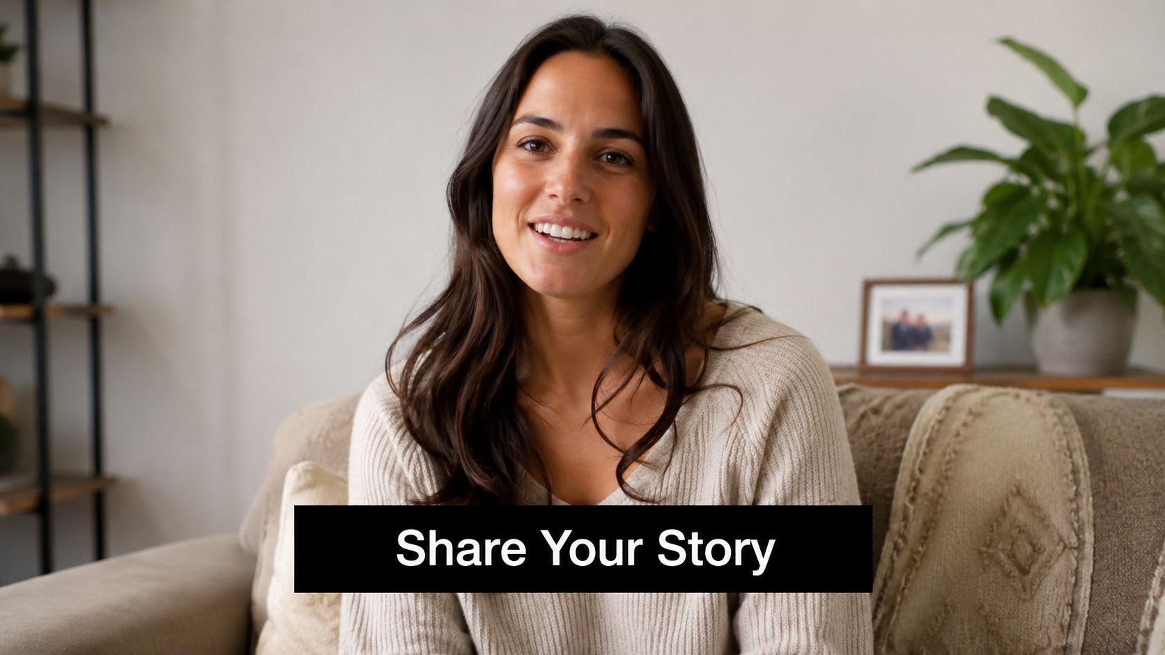 A friendly woman sitting on a couch smiling at the camera for a testimonial video request.