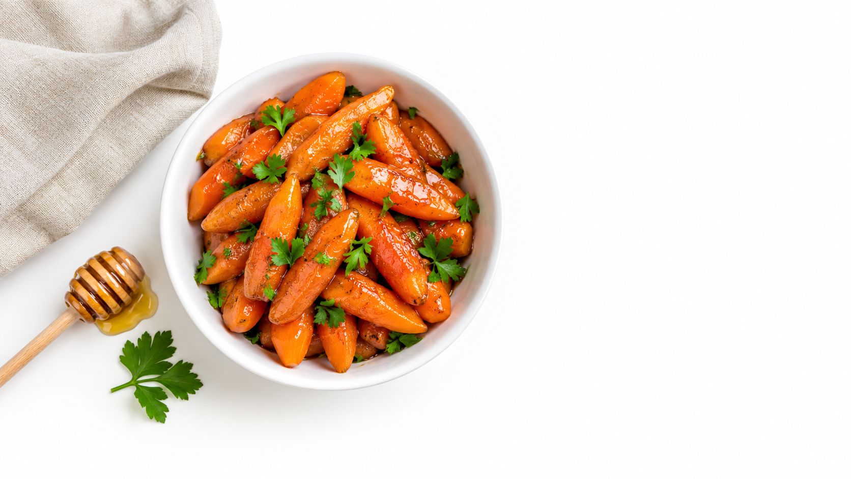A white bowl filled with glossy honey glazed carrots garnished with fresh green parsley on white background.
