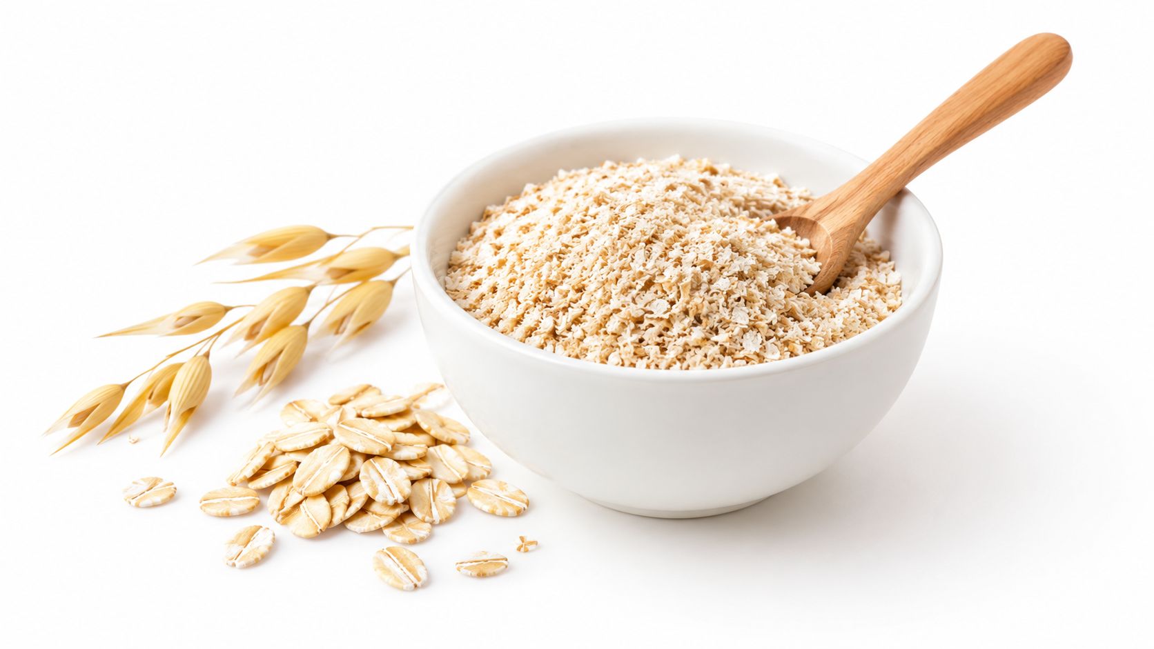 A white bowl of wheat bran with a wooden spoon alongside oat flakes and oat stalks.