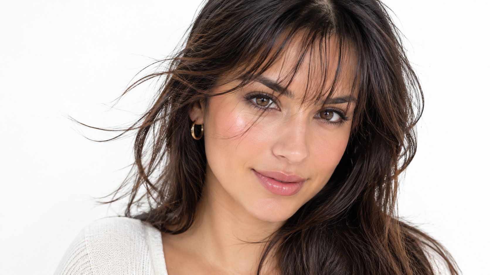 A beautiful woman with long brown hair and trendy wispy bangs posing for a professional portrait
