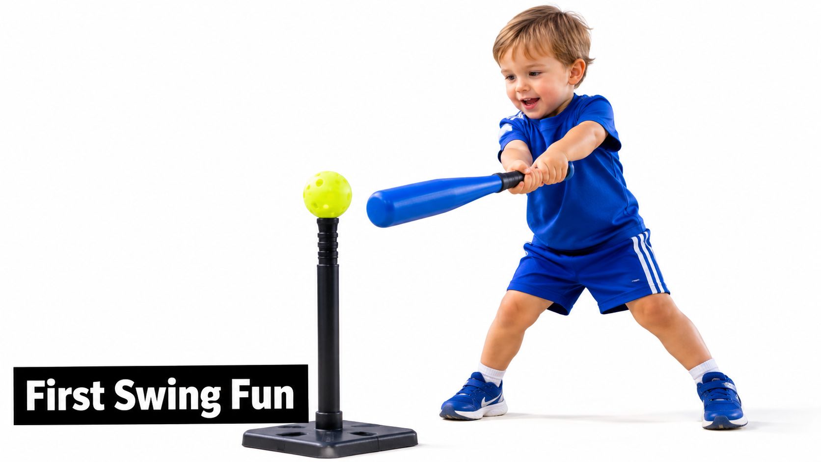 A happy young boy wearing a blue outfit swings a toy bat at a ball on a tee.