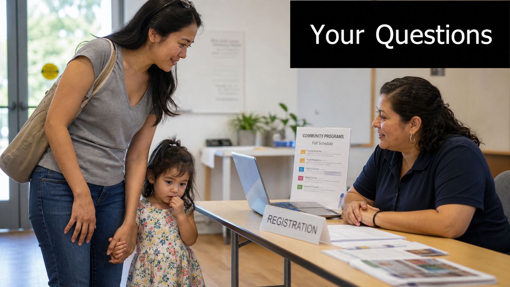 A woman and her young child speaking with a registration clerk at a community center office desk.