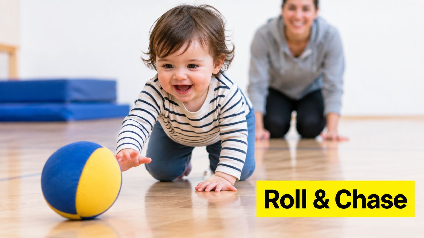A happy toddler crawling on a wooden floor reaching for a colorful blue and yellow ball.