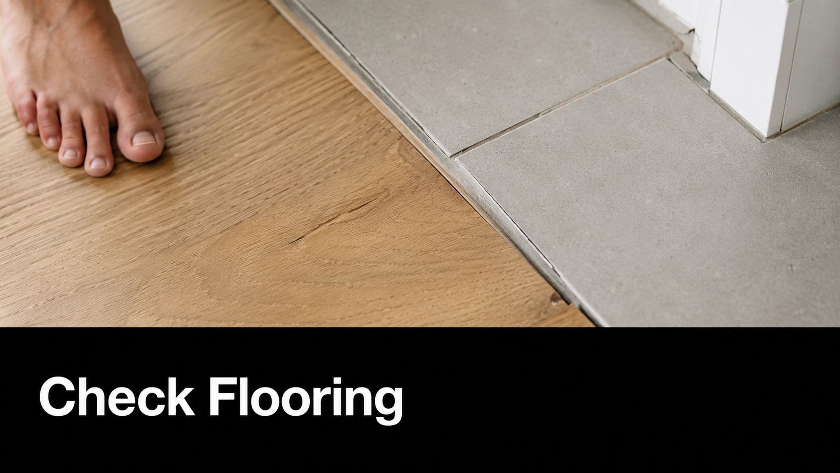 A close-up view of the transition between wooden flooring and grey tiles during an apartment inspection.