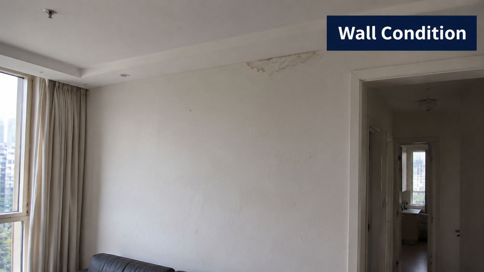 A view of an interior wall showing signs of water damage and paint peeling near the ceiling.