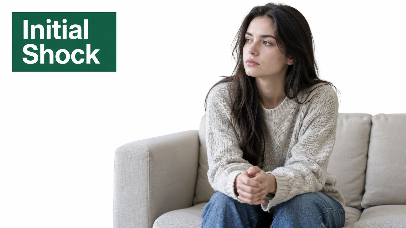 A contemplative young woman sitting on a beige couch, representing the initial shock phase of emotional recovery.