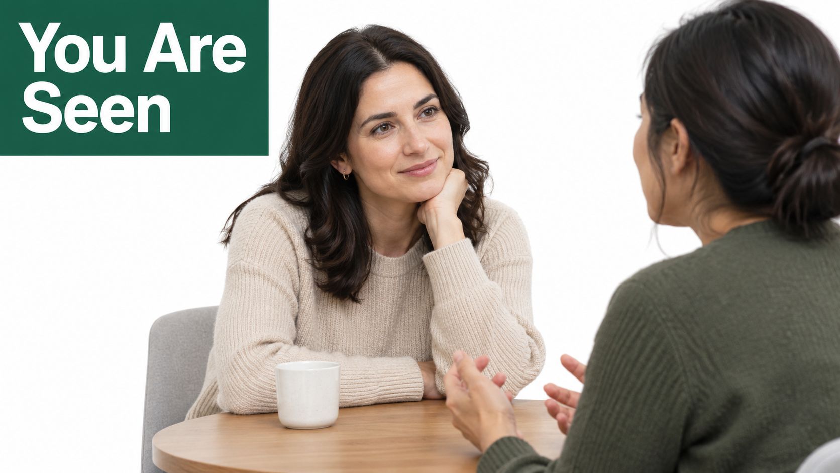 A woman listening attentively to another person during a supportive, professional conversation in a bright office space.
