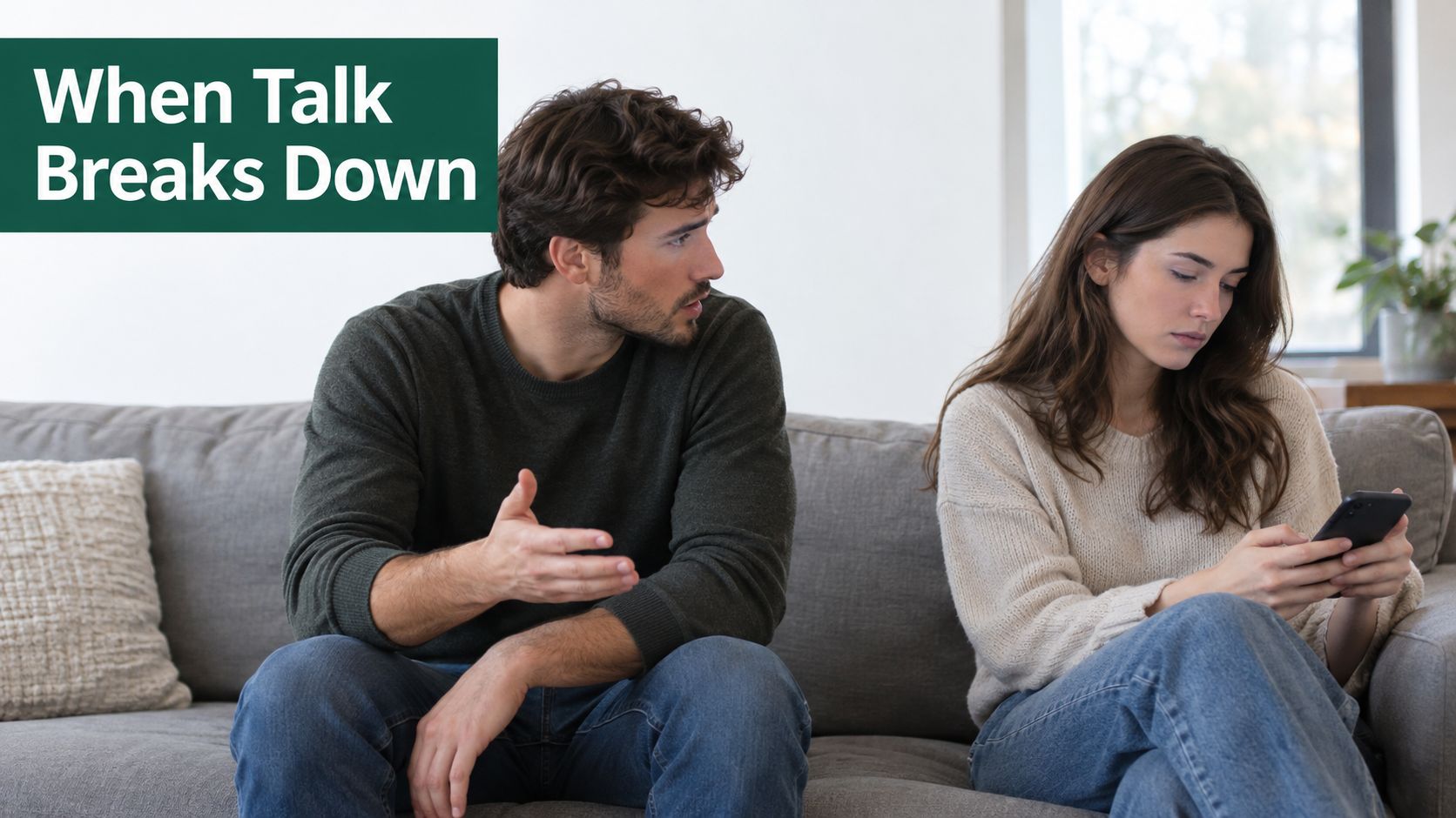 A couple sitting on a sofa looking unhappy and having communication difficulties, with the man speaking.