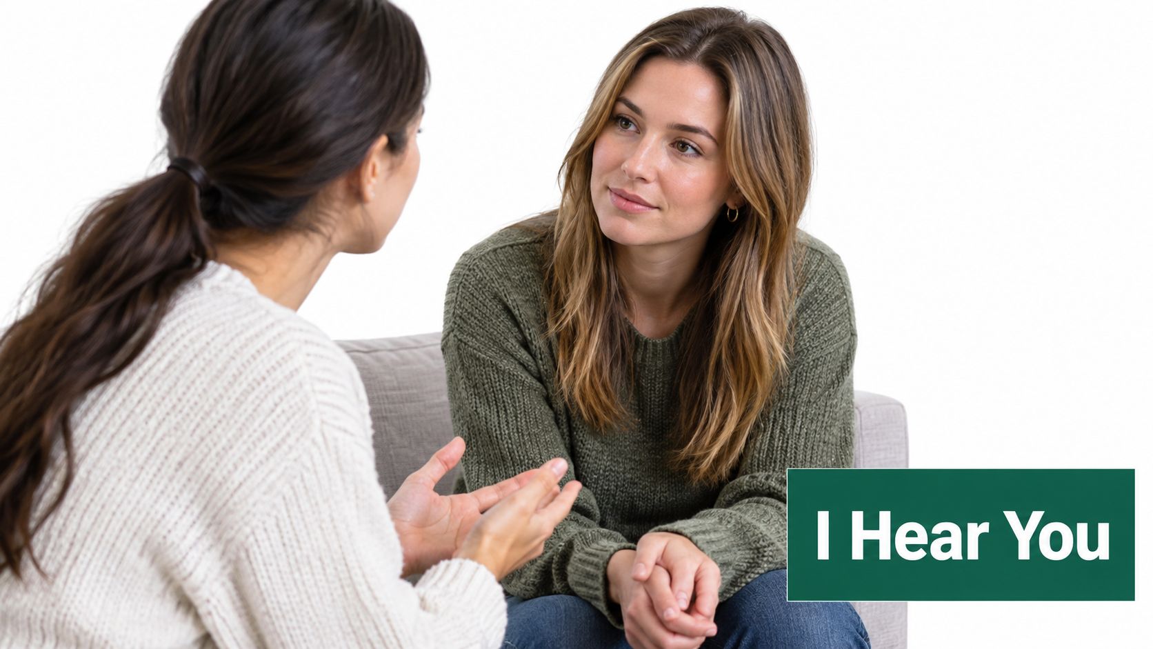 Two women sitting on a sofa engaging in a thoughtful conversation while practicing active listening techniques together.