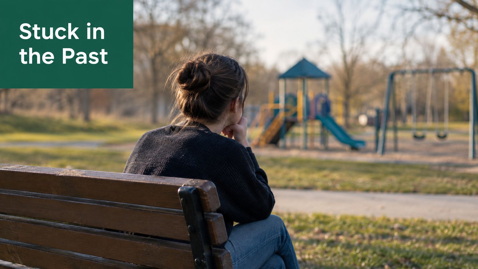 A person sitting on a park bench looking pensively towards a playground in the distance