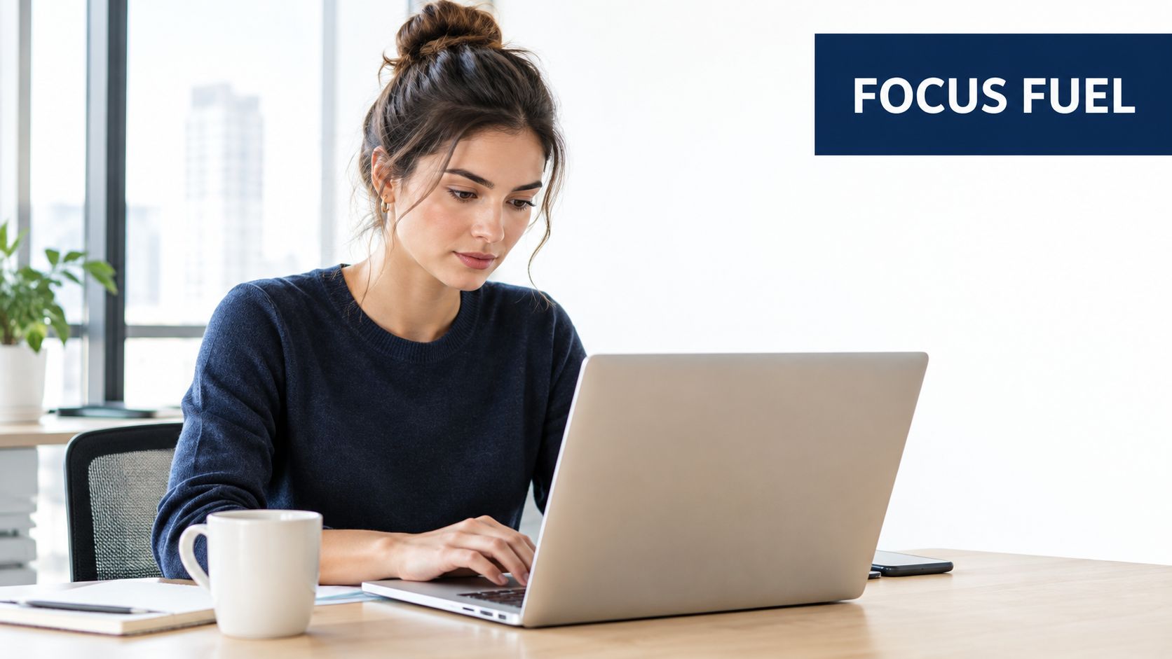 A young woman focused on her work while using a laptop at a bright office desk.