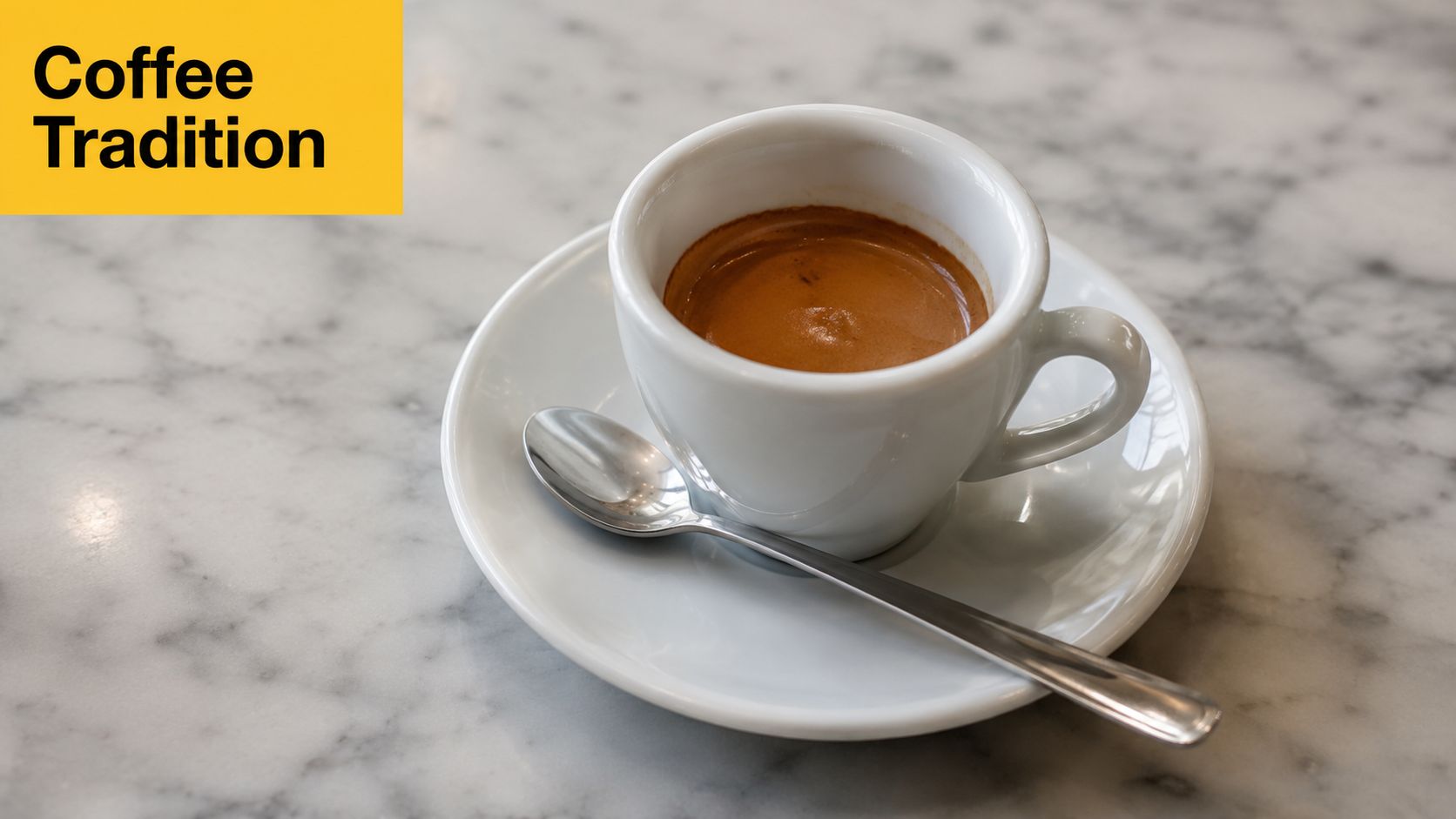 A cup of rich, dark espresso served on a white saucer with a metal spoon on marble table.