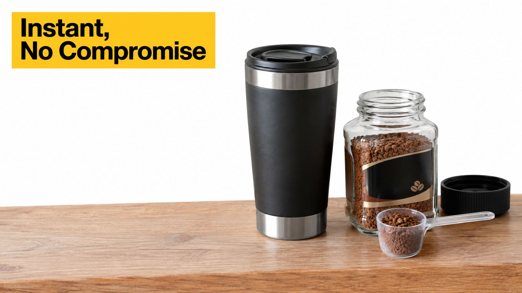 A black travel mug, a glass jar of instant coffee, and a scoop on a wooden table.