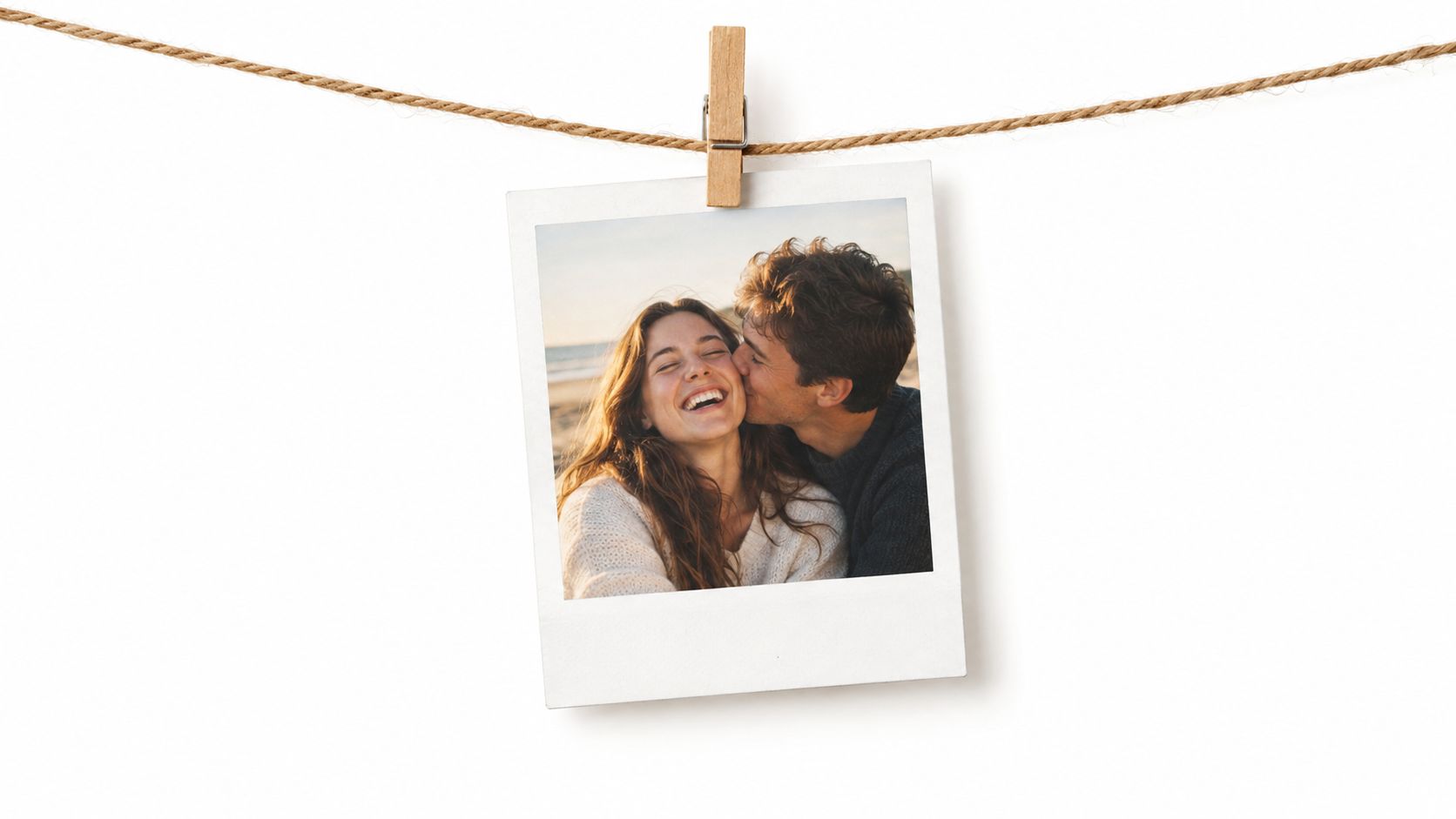 A happy couple hugging and kissing while captured in a vintage polaroid photo hanging on a rope.