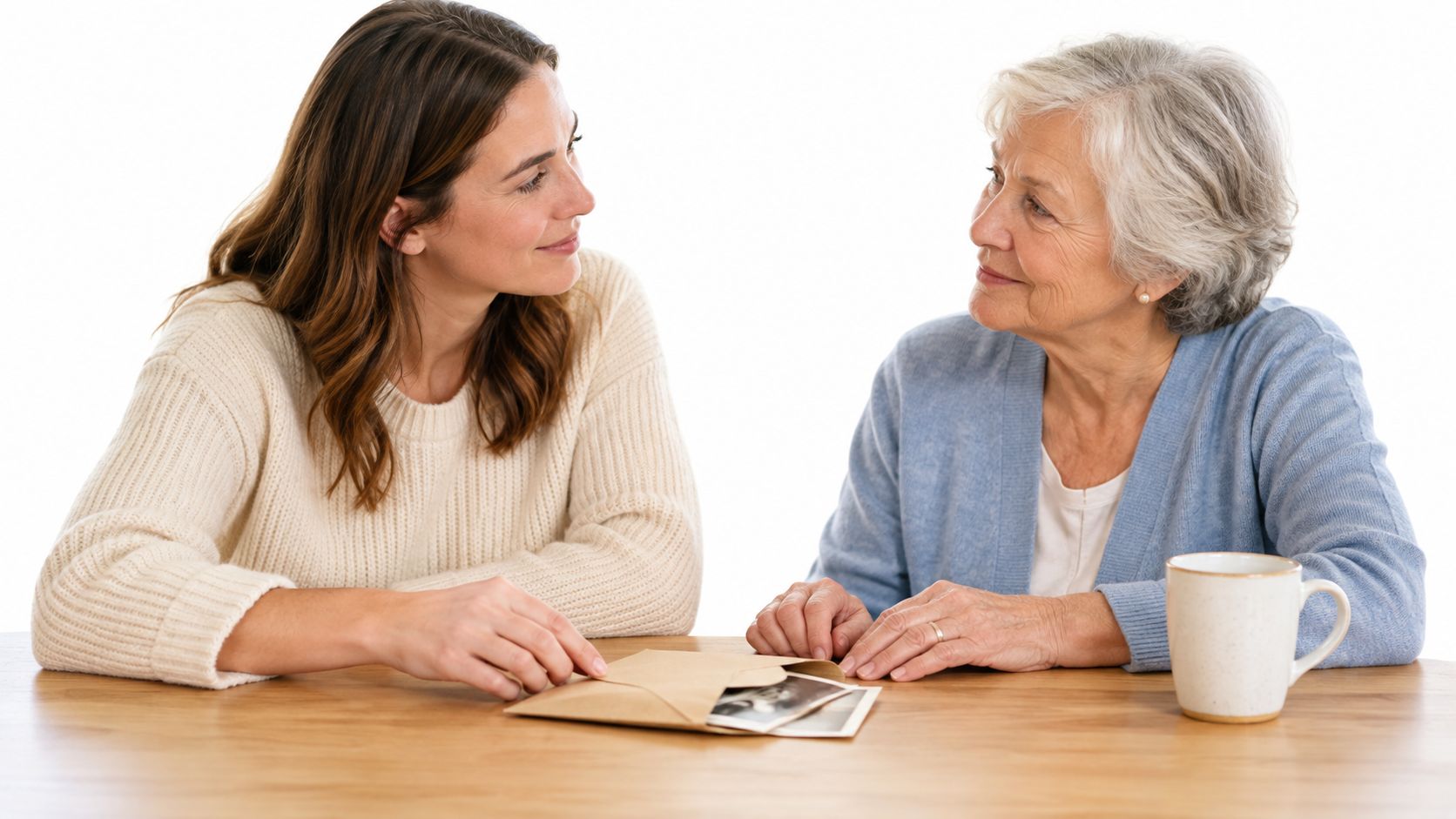 A young woman and an elderly woman sitting at a table together while sharing old photographs.