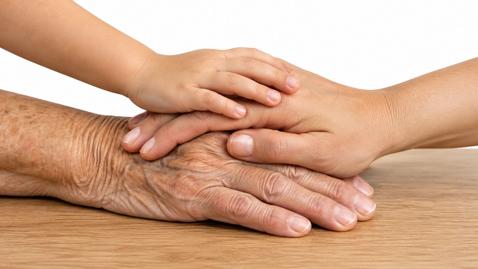 A gentle shot of a child's hand resting on an adult's hand, placed upon an elderly person's hand.