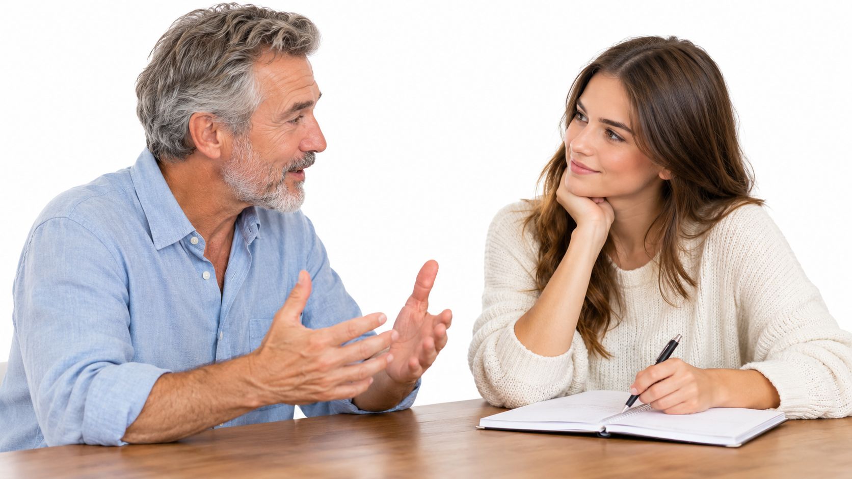 An older man explaining something to a young woman who is writing in a notebook during an interview.