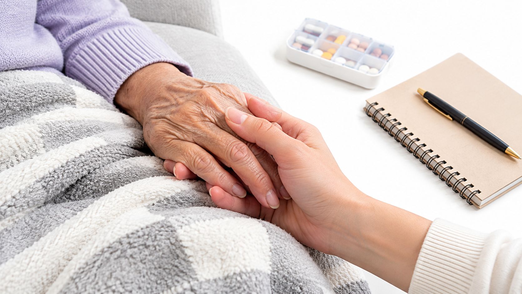 A close-up of a caregiver gently holding the hand of an elderly person for emotional support.