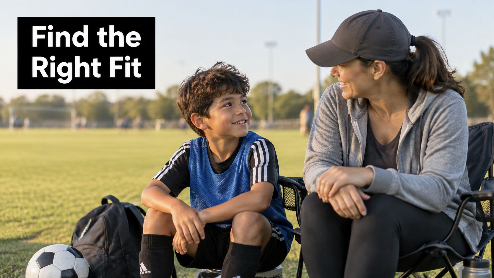 A young soccer player and his mother smiling at each other while sitting on the sidelines.