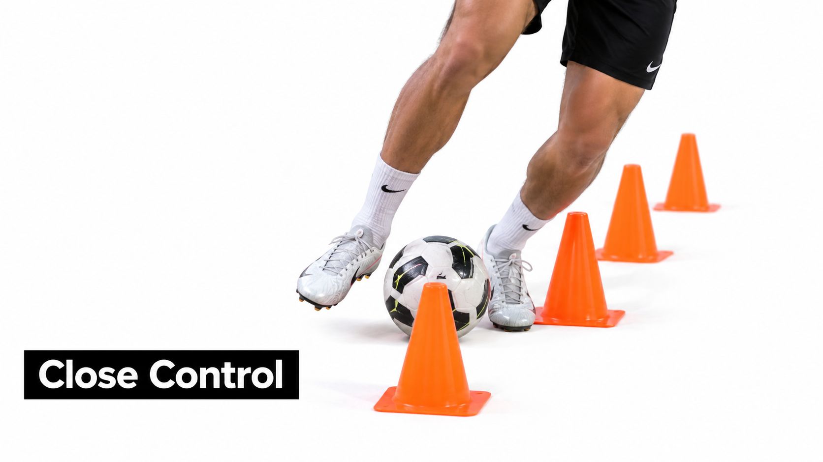 A soccer player practices close control dribbling drills by weaving a ball through orange plastic cones.
