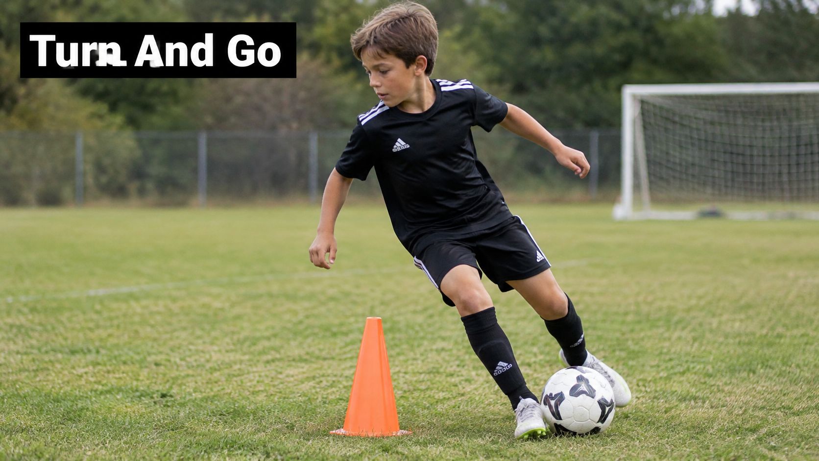 A young boy practicing soccer drills by turning around an orange cone with a soccer ball.