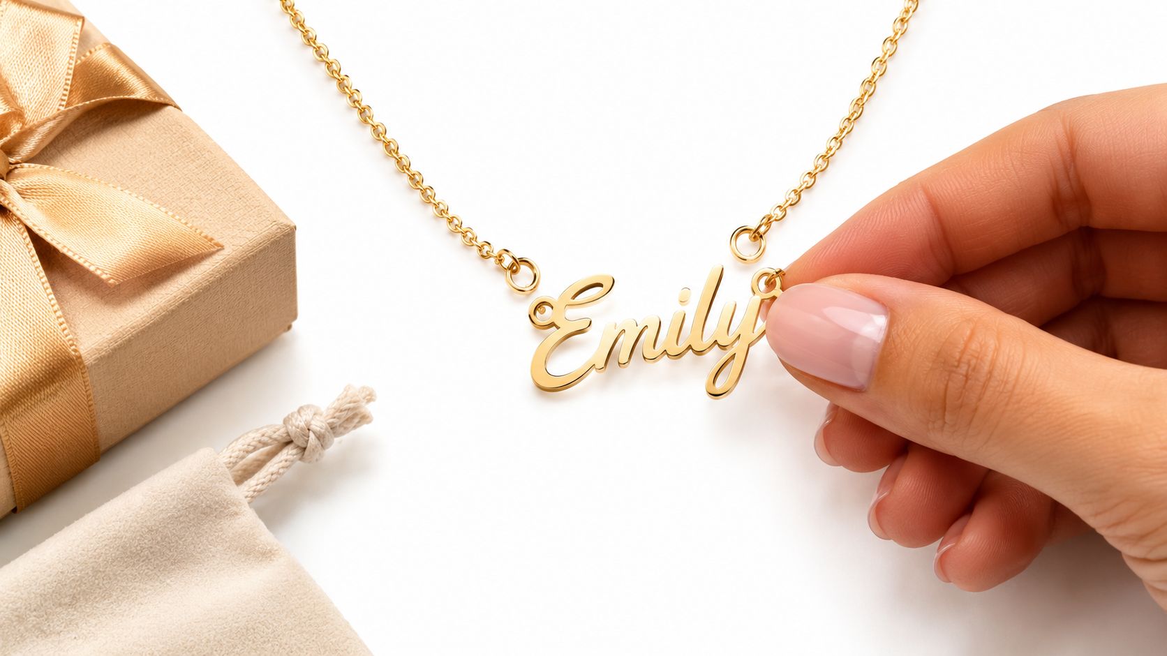 Un collier doré portant le prénom Emily est présenté par une main devant un cadeau.