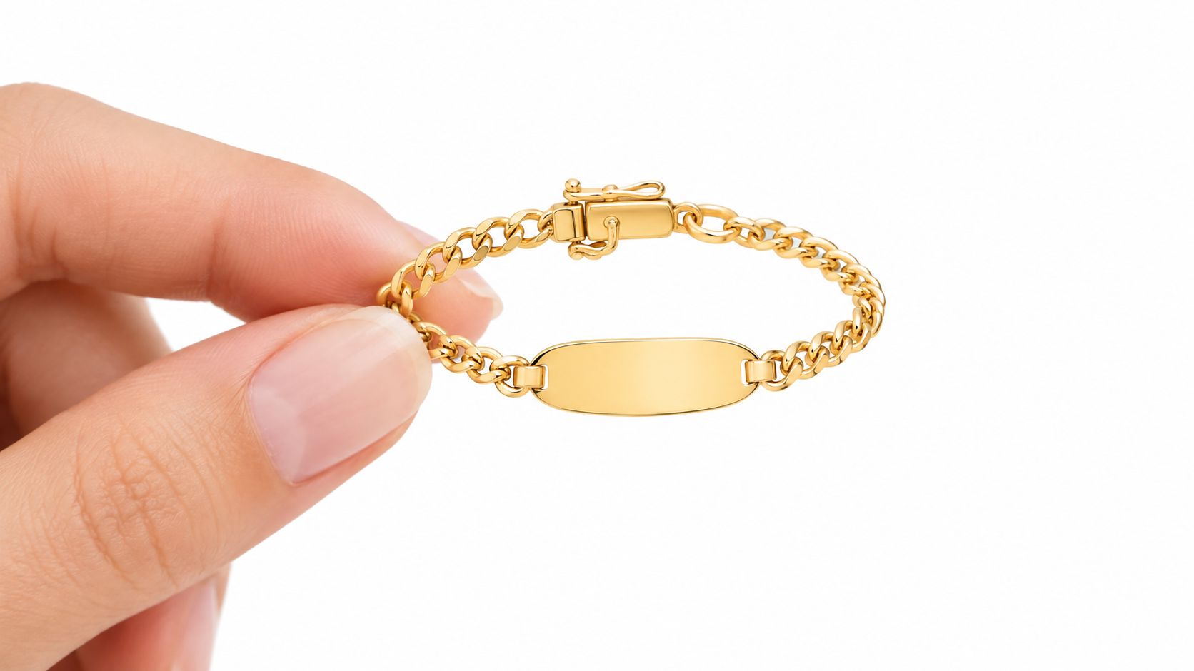 Una elegante pulsera de oro para bebé con una placa de grabado vacía, sostenida entre el pulgar y el índice de una mano.