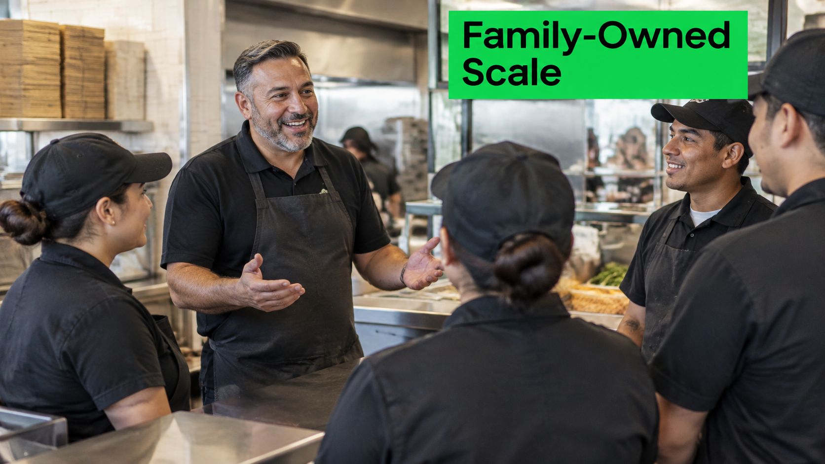 A friendly business owner speaking to his restaurant staff during a team meeting in a kitchen.