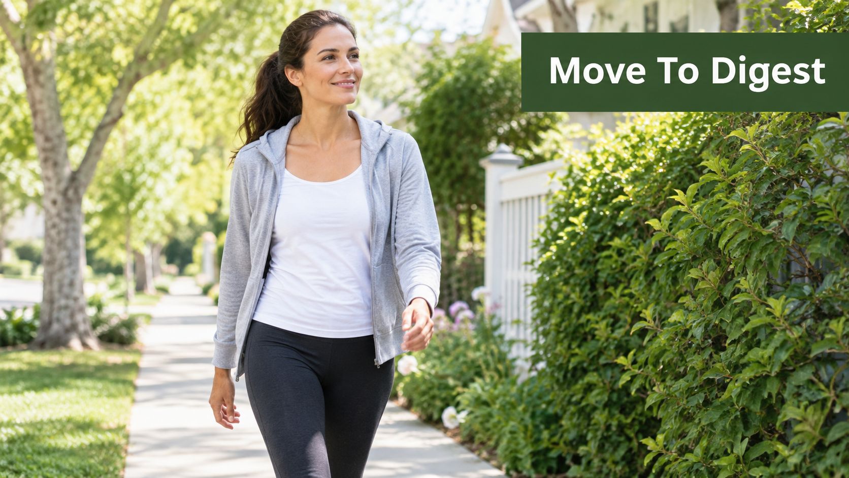 A fit woman walking along a sidewalk, wearing a gray zip-up hoodie and dark workout leggings.