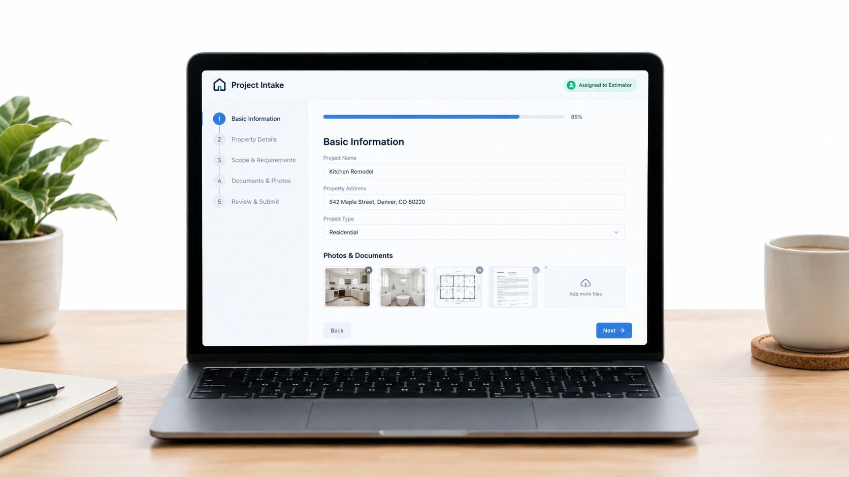 A laptop on a wooden desk displaying a project intake web interface with form fields and documents.